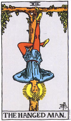 Carte du Pendu : un homme suspendu par le pied à un arbre en tau, jambe repliée, bras croisés dans le dos, visage serein entouré d’une auréole de lumière.